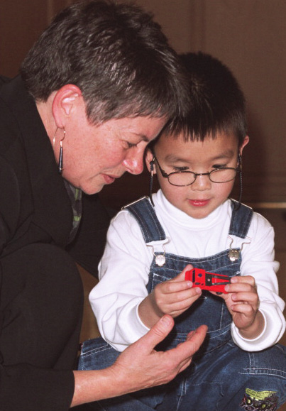 A young boy is seen playing with a toy truck with Dr. Brenda Gallie, the physician that led his treatment.