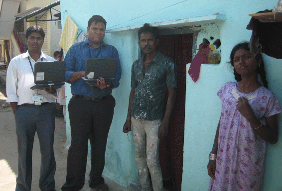 A group of researchers (two holding laptops) stand ouside of the front door of a house.