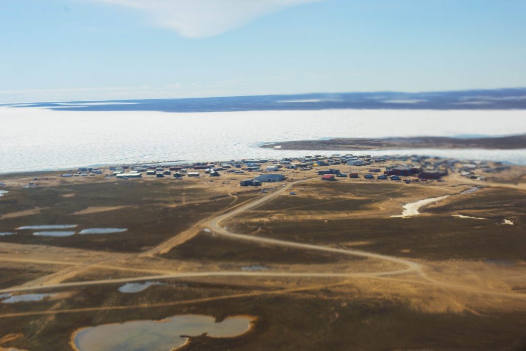 Panoramic skyline of the far north. Ice covers the ground and a lone man is seen in the distance.