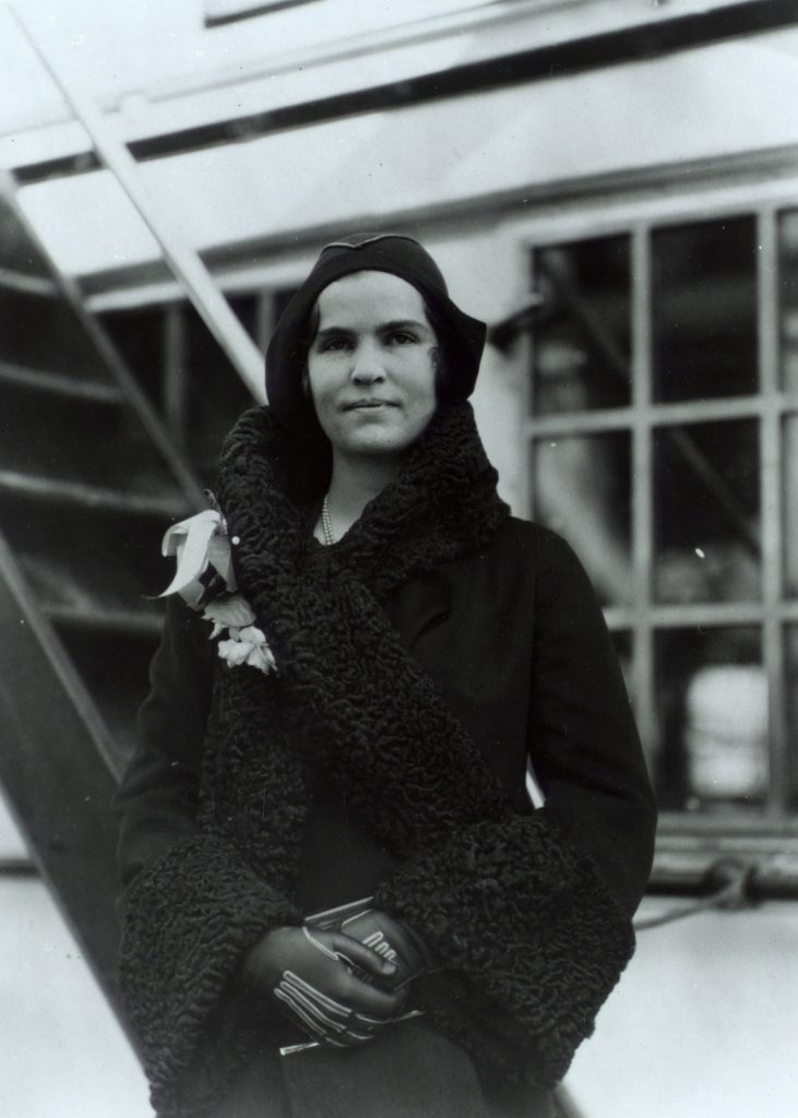 In December 1930, a healthy-looking Elizabeth Hughes wears fashionable clothes and stands on the deck of a passenger ship.