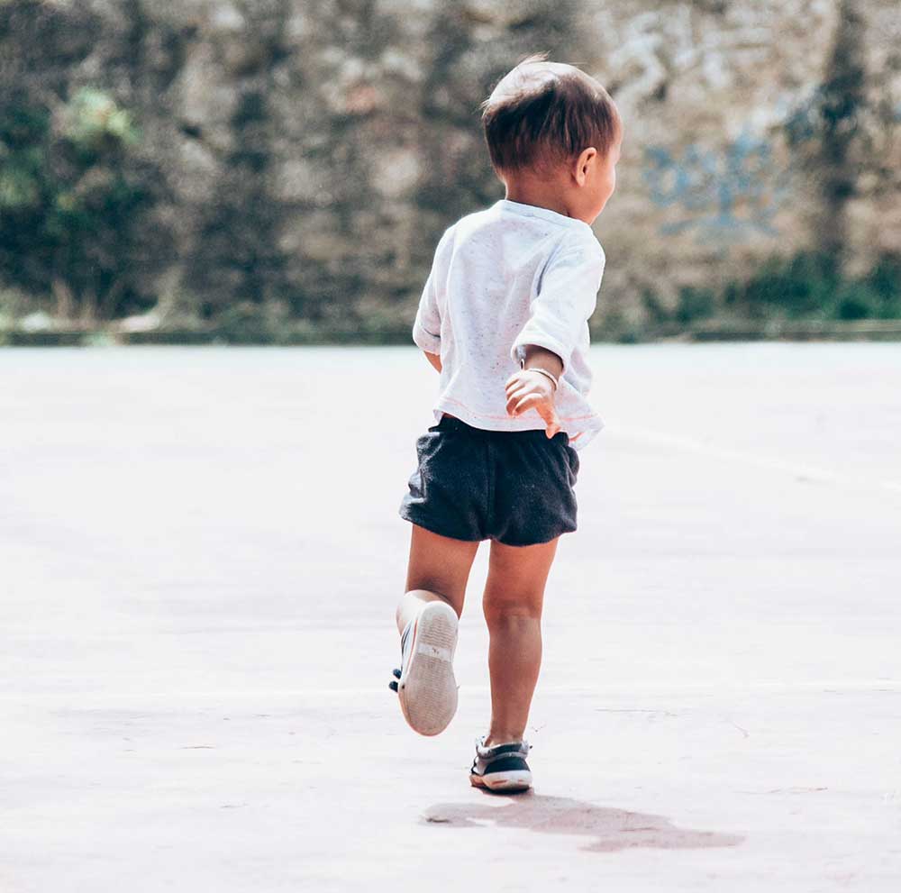 A young boy running outdoors.