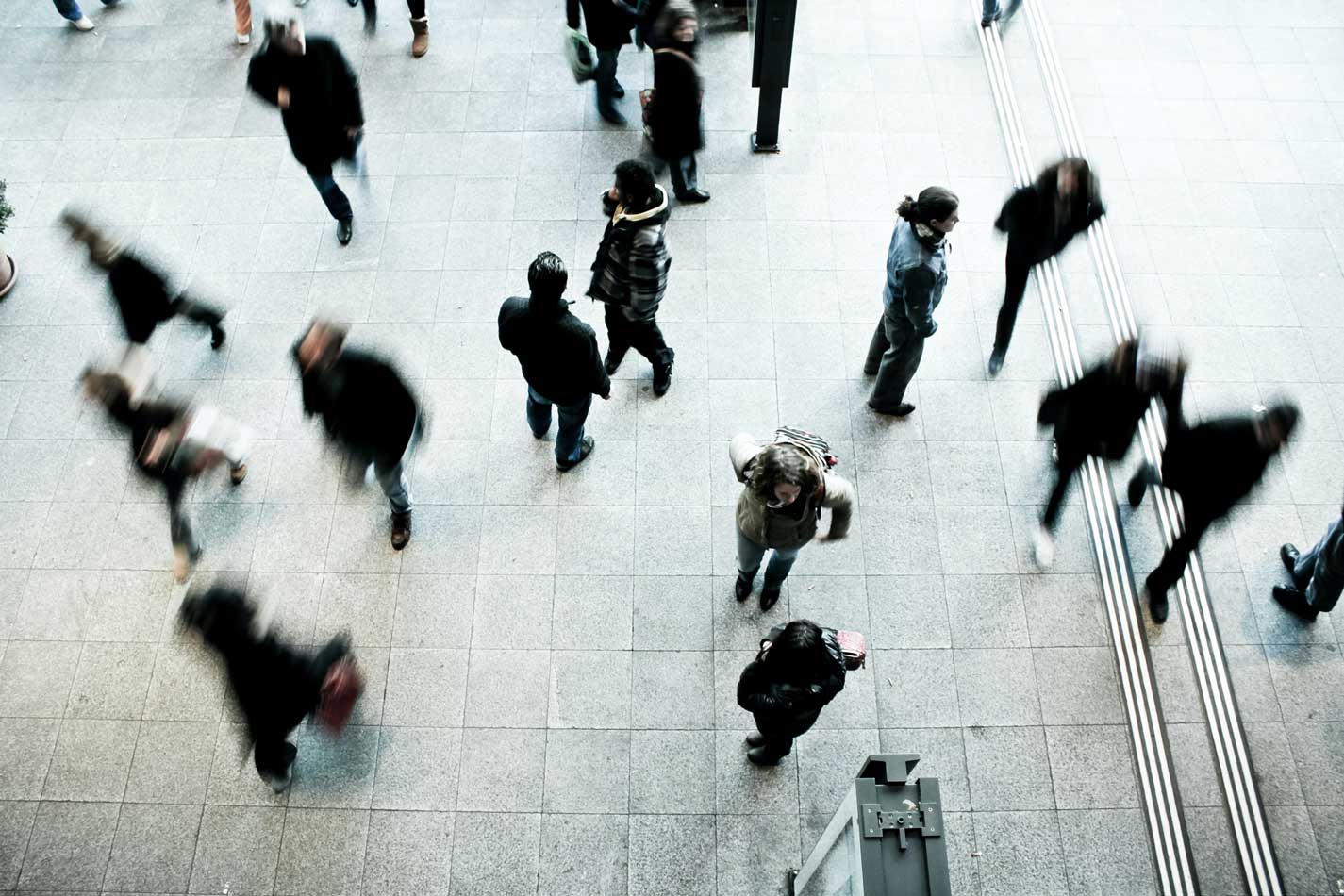 An aerial shot of a crowd of people walking in a busy plaza.