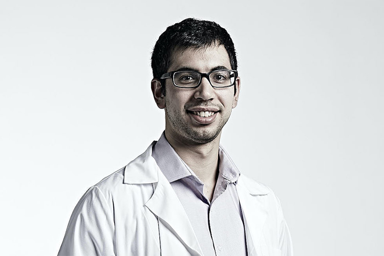 Portrait of Ilias Ettayabi, wearing a physician's white coat and smiling.