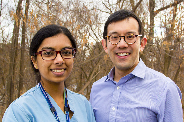 Kirusanthy Kaneshwaran and Andrew Lim stand side by side in a forest, smiling.