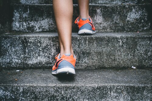 Woman's feet climbing stairs in running shoes